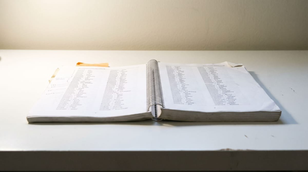 Hawaiian translation visual: A spiral-bound pronunciation reference opened flat at a two-column page.
