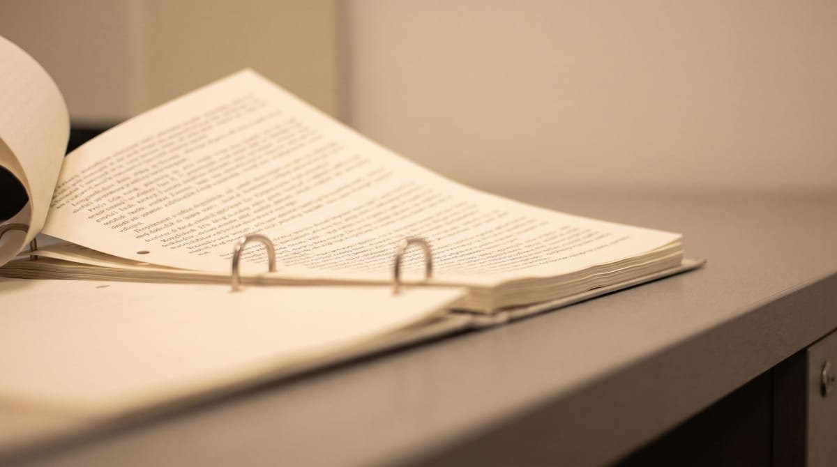 Shona translation visual: A punched page set held on two posts with the top sheet lifted clear.